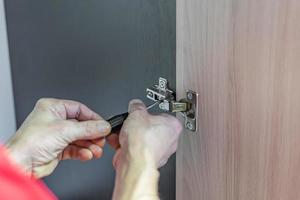 Closeup of worker's hands fitting wardrobe hinge doors in closet photo