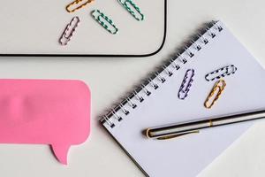 top view of white office desk, pink sticker for notes, laptop, pen and notebook, business mockup photo