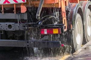 close up of street cleaning sweeper machine washes the asphalt road photo