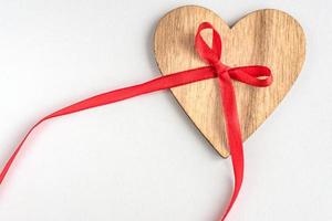 wooden heart with red ribbon bow on white background photo