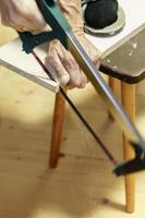 man sawing a board with a hacksaw photo