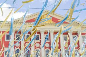 blue and gold strips of cloth hanging on a string on red building background photo