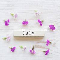 top view of wooden calendar with July sighn and pink flowers. photo