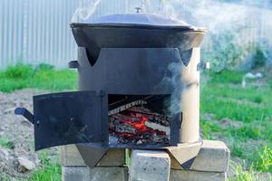 Big metal cauldron pot on movable stove outdoors photo