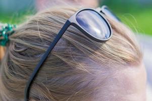 Cerca de gafas de sol negras en la frente de una joven rubia foto