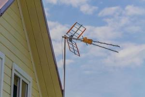 antena de tv en el techo de una casa de campo contra el cielo azul foto