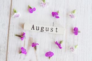 vista superior del calendario de madera con suspiro de julio y flores rosas. foto