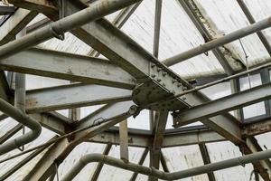 metal and glass roof of a greenhouse with pipes photo