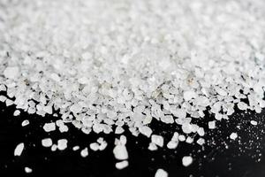close up of sea salt for cooking and aromatherapy on black wooden background photo
