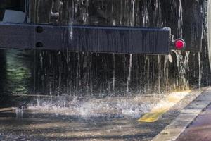 close up of street cleaning sweeper machine washes the asphalt road photo