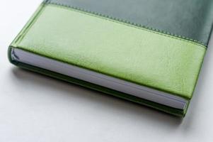cuaderno de notas de negocios verde sobre la mesa blanca foto