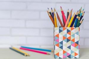 Canister full of colored pencils on table photo