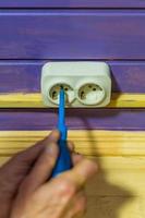 Closeup of man's hand installing socket on wooden wall at country house photo