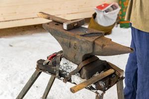 blacksmith manually forging the molten metal on the anvil outdoors photo