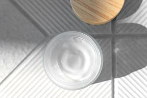 Top view of open glass jar with face cream with peptides for anti aging effect on concrete background. Minimalism style. photo