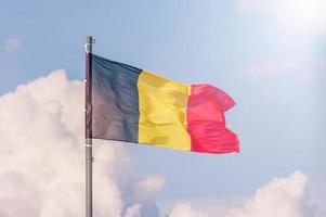 la bandera nacional de bélgica ondea sobre el cielo azul foto