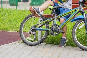 jovencito descansando en un banco con bicicleta foto