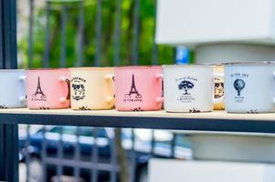 multicolored enamel cups standing in a row on a shelf. Cups with decoration and lettering photo