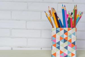 Canister full of colored pencils on table photo