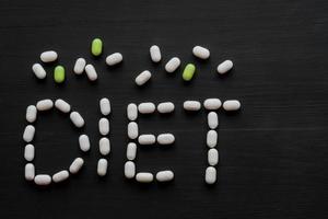 Medical concept written with pills  word DIET On black wooden background with copy space photo