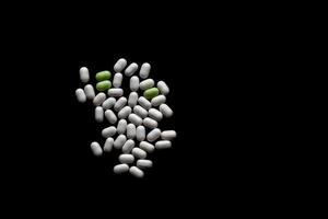 white and green pills On black wooden background with copy space photo