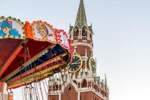 torre spasskaya del kremlin y carrusel de tiovivo en la plaza roja de moscú foto