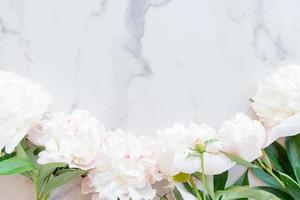 Flat lay composition with pink peony flowers on a marble background with copy space for text or design photo