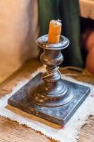 Extinguished candle in candlestick on wooden table photo