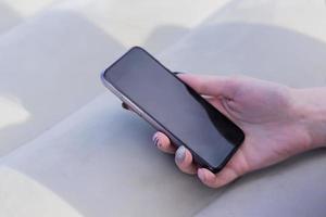 female hand with manicure holding black smartphone photo