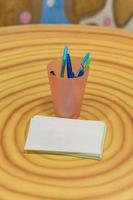 Bunch of color pens in a stand on wooden round table photo