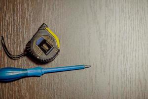 screwdriver and measuring tape on wooden background photo