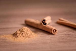 palitos de canela y polvo sobre mesa de madera. enfoque suave foto