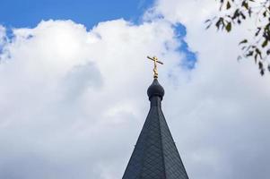 cruz ortodoxa en cúpulas contra el cielo azul con nubes foto