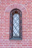 pared de ladrillo rojo del edificio con ventana de madera detrás de la celosía metálica foto