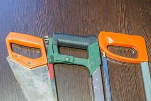 three various handsaws on wooden background photo