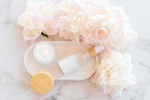 Natural organic cosmetic products with essential peony oil. Skin care cosmetics on concrete tray with flowers. photo