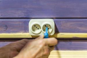 Closeup of man's hand installing socket on wooden wall at country house photo