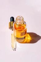 Summer vitamin C cosmetic product and template. Open dropper bottle mock-up displayed on a pink background photo