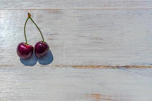 blue plate of ripe sweet cherry on white wooden table photo