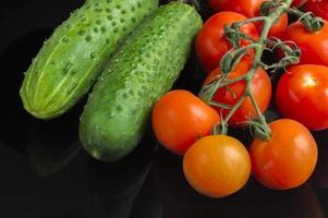 red toatoes and green cucumbers on black background photo