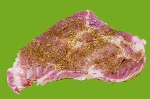 Raw pork steak with spices on green background photo