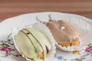 eclairs franceses en plato de porcelana de colores sobre mesa de madera. foto