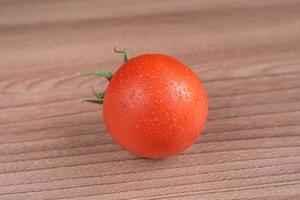 Red tomato with drops of water on wooden bckground photo