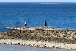 People rest on the shores of the Mediterranean Sea photo