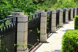 Plants and flowers grow along the high fence. photo