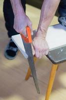 man sawing a board with a hacksaw photo