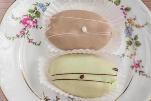 eclairs franceses en plato de porcelana de colores sobre mesa de madera. vista superior foto