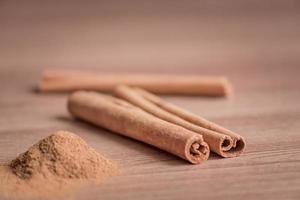 cinnamon sticks and powder on wooden table.