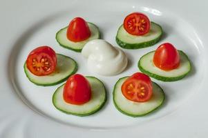 Cherry tomatoes an sliced cucumbers with mayoneese sauce on a plate. Fresh salad photo