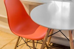 closeup of cafe interior. Plastic orange chair and round white table in modern style photo